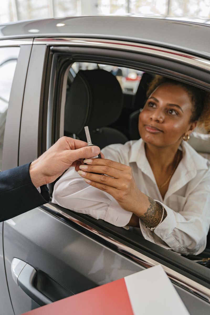 Student receiving car keys at dealership buying first car
