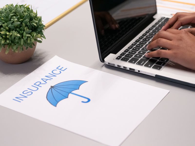 Insurance documents and laptop on desk