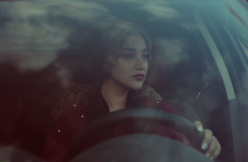 Young man and woman smiling by a car
