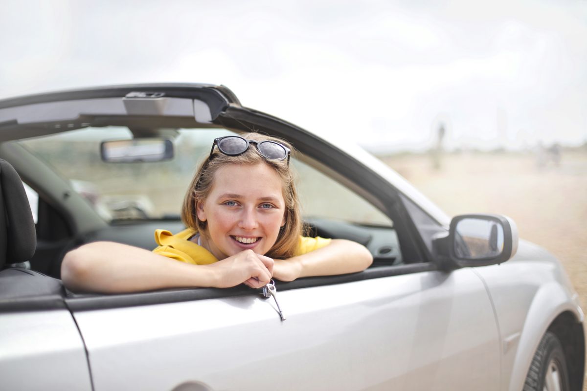 College student smiling while riding in a convertible on a sunny day