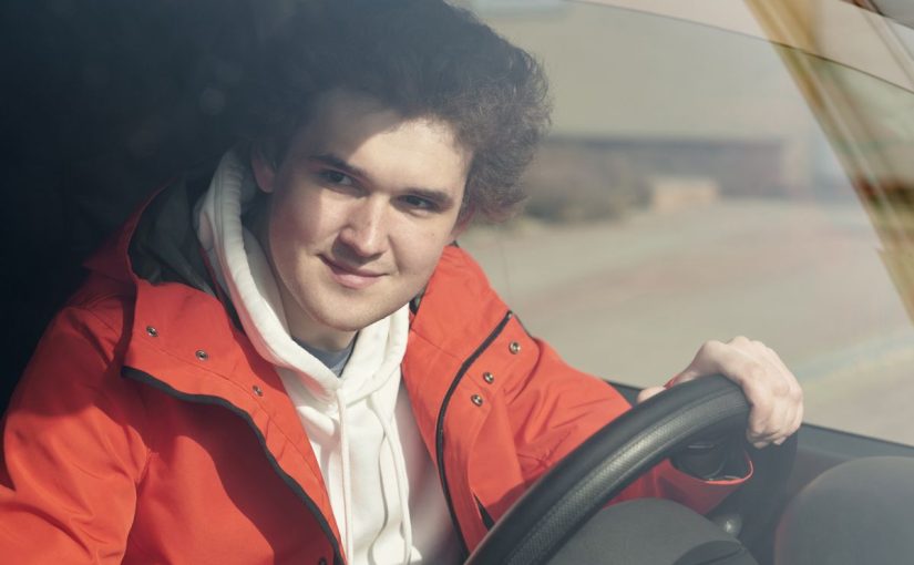 Young driver standing beside a car