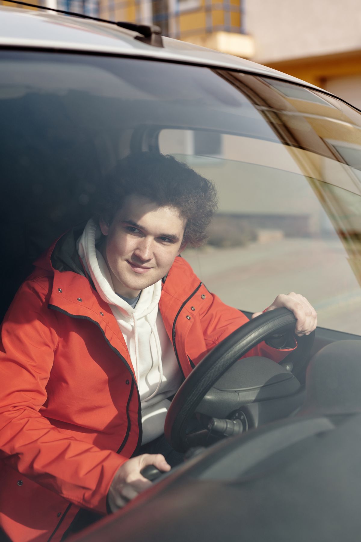 Young driver standing beside a car