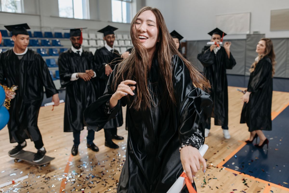 College graduate in cap and gown on campus